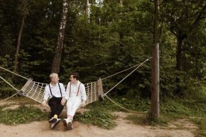 Two men in love sitting in a hammock in a lush forest, enjoying nature and each other's company.