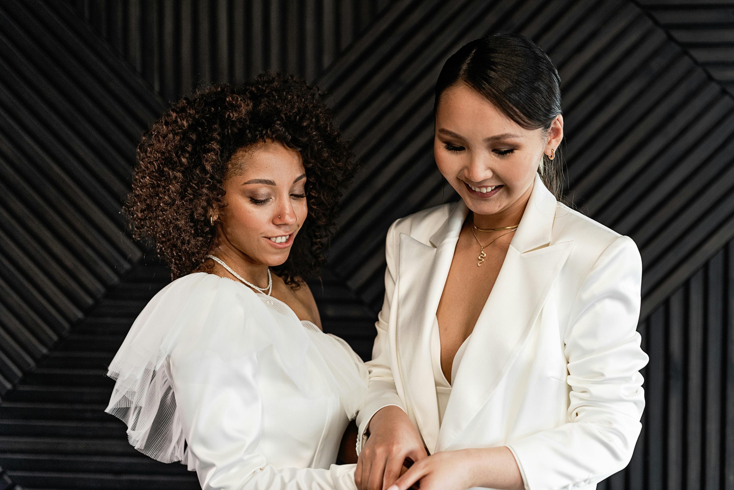 Beautiful lesbian couple joyfully celebrating their wedding day in elegant attire, symbolizing love and diversity.